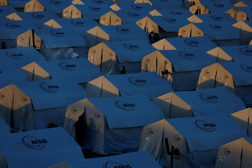 Displaced people walk outside tents at a camp for earthquake survivors at KSU Avsar university campus in the aftermath of a deadly earthquake in Kahramanmaras, Turkey, March 9, 2023.