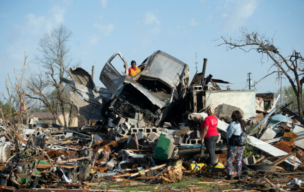 KeUntey Ousley tries to salvage what he can from his mother's boyfriend's vehicle, as his mother LaShata Ousley and his girlfriend Mikita Davis watch, after a tornado cut through their small Delta town the night before in Rolling Fork, Mississippi, U.S. March 25, 2023. Barbara Gauntt/USA Today Network via REUTERS