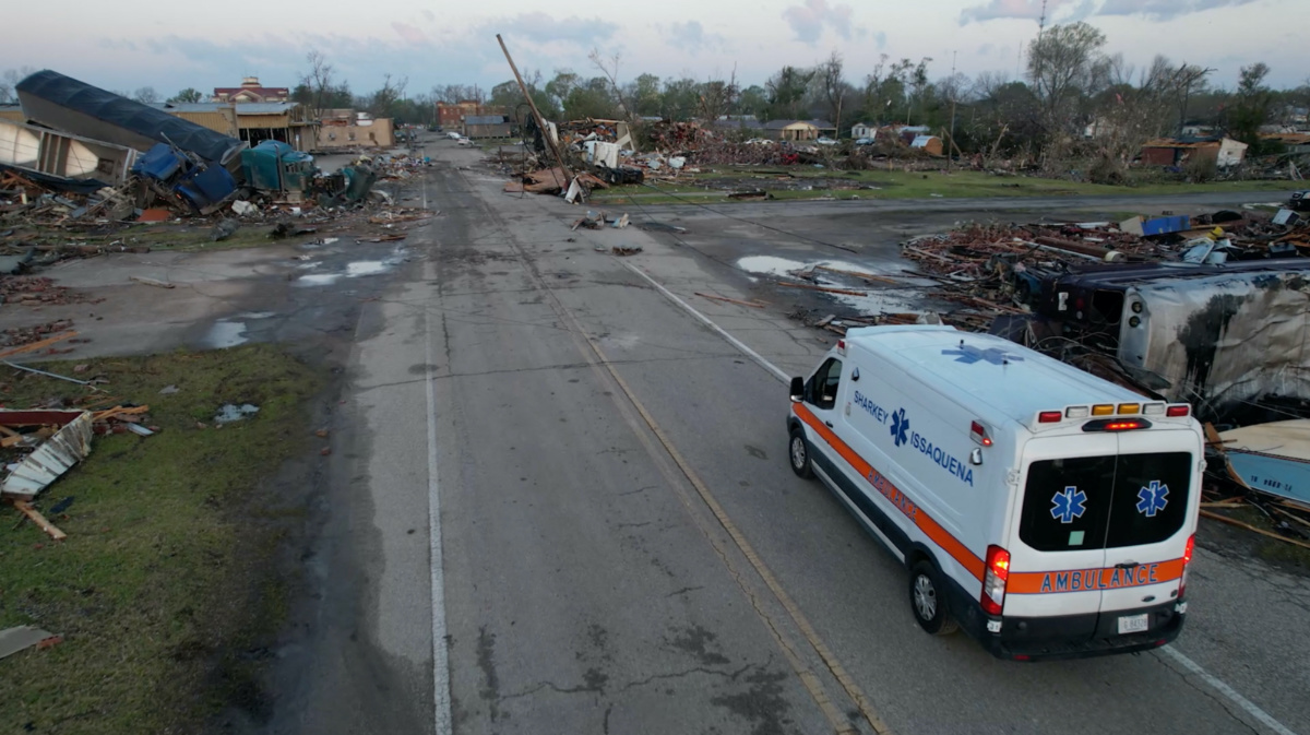 An ambulance drives along a road, near destroyed buildings and vehicles, in the aftermath of a tornado, in Rolling Fork, Mississippi, U.S. March 25, 2023 in this screengrab obtained from a video. SevereStudios.com / Jordan Hall/via REUTERS
