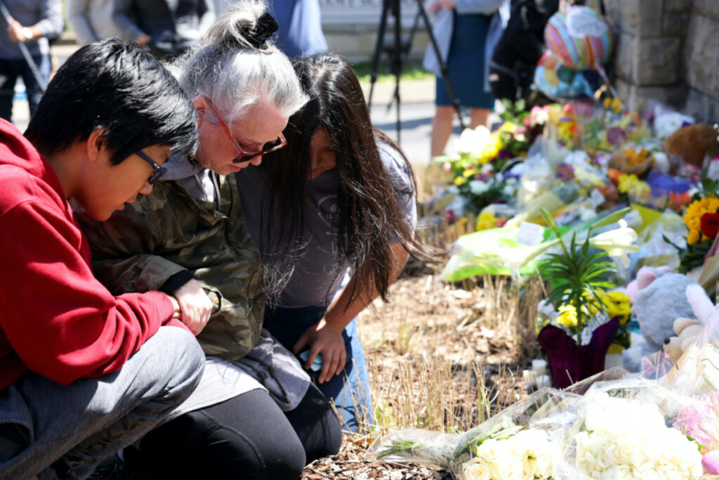 Shepherd Hollis, Katie Jo Hollis, and Sophie Hollis pray at the memorial for the fallen at the school entrance after a deadly shooting at the Covenant School in Nashville, Tennessee, US, on 28th March, 2023.