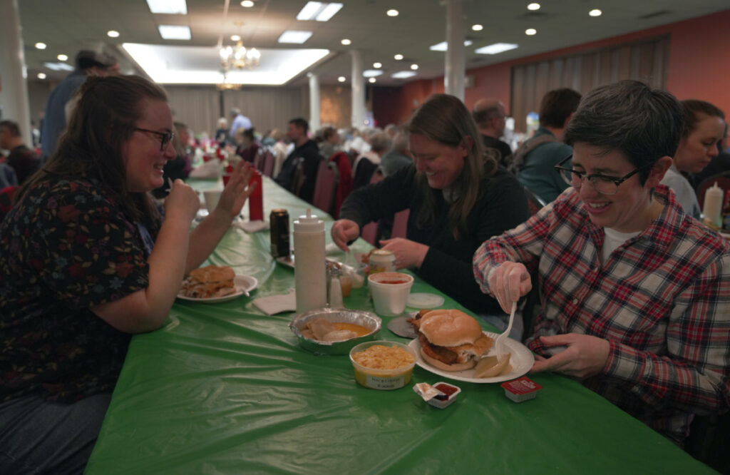 From left, Laura Kuster, Miranda Crotsley, and Hollen Barmer eat fish sandwiches, homemade perogies, and macaroni and cheese at the St Maximilian Kolbe Catholic Church fish fry in the West Homestead neighborhood of Pittsburgh, on Friday, Feb. 24, 2023.