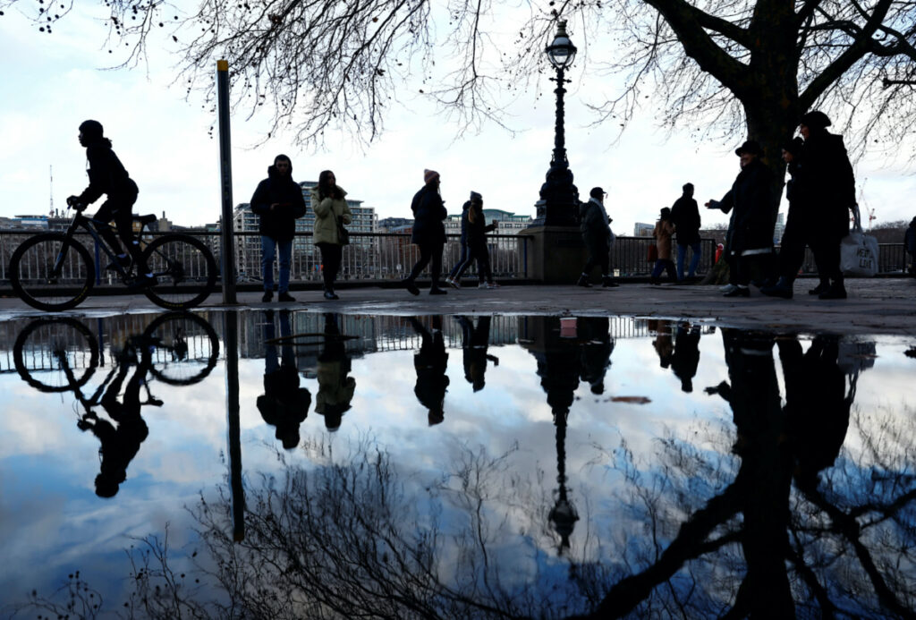 FILE PHOTO: Visitors to the Southbank are seen reflected in rainwater, in London, Britain, December 29, 2022. REUTERS/Peter Nicholls