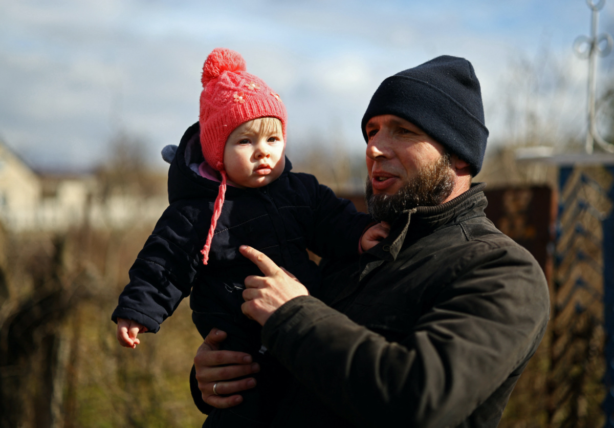 Oleksii Markelov holds his daughter baby Kateryna, who was born during the Russian occupation, as he stands next to their house amid Russia's invasion of Ukraine, in Antonivka, Kherson region, Ukraine, February 21, 2023. REUTERS/Lisi Niesner