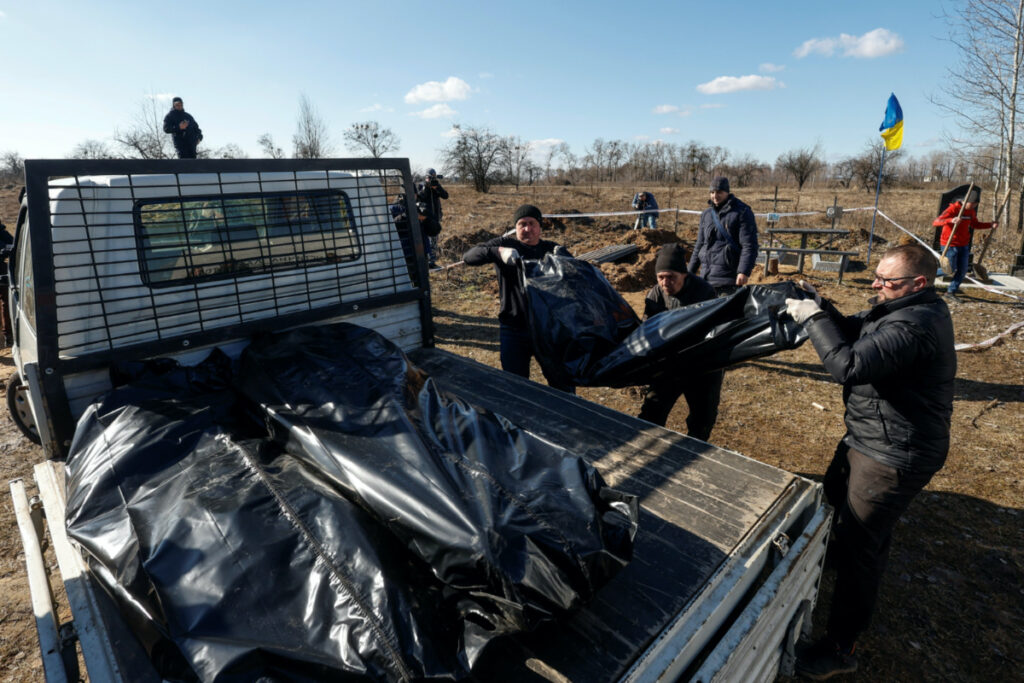 Volunteers carty the bodies of people who were buried by a local resident during the Russian occupation of the town of Borodyanka last year, amid Russia's attack on Ukraine, after an exhumation at the town's cemetery, outside of Kyiv, Ukraine, March 2, 2023. REUTERS/Valentyn Ogirenko