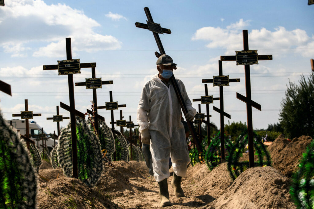 A volunteer places a cross with a number to a grave of one of unidentified people killed by Russian troops, as Russia's attack on Ukraine continues, during a mass burial ceremony in the town of Bucha, in Kyiv region, Ukraine, on 2nd September, 2022.