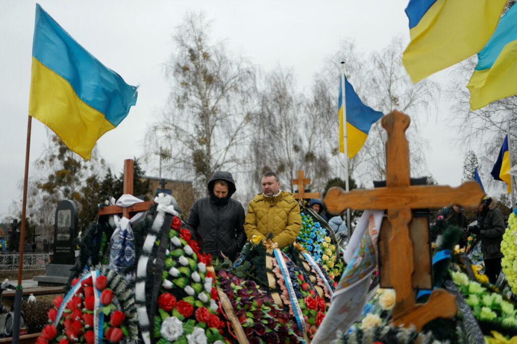 People visit the graves of their relatives, Ukrainian service members killed in fights against Russian troops, on a day of the first anniversary of Russia's attack on Ukraine, at a cemetery in the town of Bucha, outside Kyiv, Ukraine February 24, 2023. REUTERS/Valentyn Ogirenko