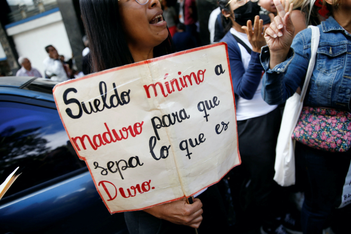 FILE PHOTO: A teacher holds a sign reading "Minimum wage to Maduro to let him know how hard it is" during a protest demanding better salaries in Caracas, Venezuela February 23, 2023. REUTERS/Leonardo Fernandez Viloria