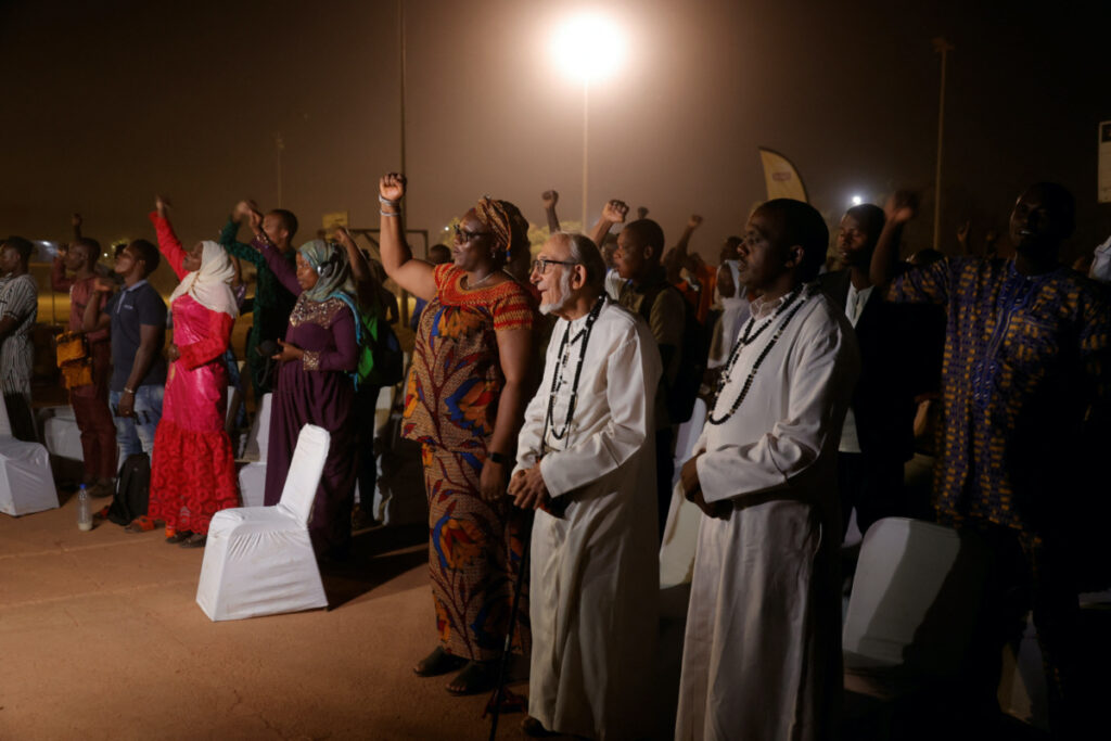 Burkinabe Muslims and Christians chant the national anthem while they gather to break the fast together in hopes of promoting religious tolerance during the Ramadan in Ouagadougou’s public square, Burkina Faso March 31, 2023.REUTERS/ Yempabou Ouo