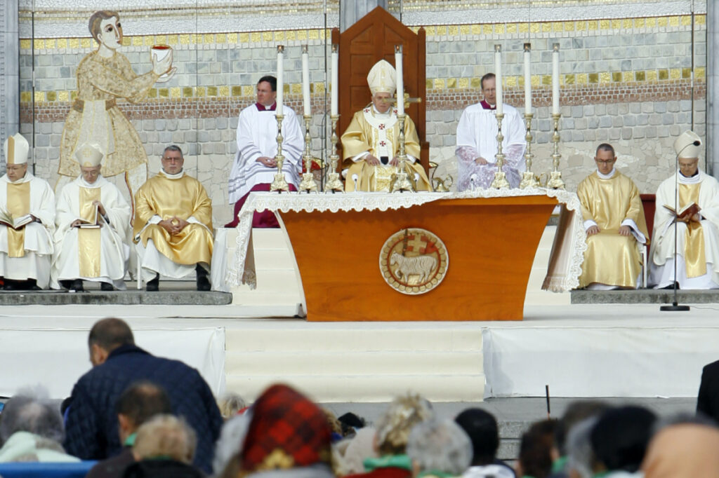 FILE - Pope Benedict XVI, center, celebrates a Mass in front of the Basilica of the Rosary in Lourdes, southwestern France, on Sept. 15, 2008. Behind him is one of the mosaics by Rev. Marko Ivan Rupnik, who was declared excommunicated in 2020 for committing one of the worst crimes in church law – using the confessional to absolve a woman with whom he had engaged in sexual activity. Officials at the Catholic shrine in Lourdes, France announced the creation of a study group Friday, March 31, 2023, to decide what to do with the sanctuary’s mosaics, its most famous but now controversial attraction. (AP Photo/Alessandra Tarant