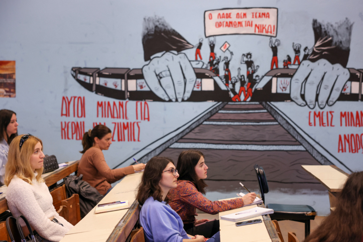 Students attend a class as a graffiti depicts two trains about to collide at the Aristotle University of Thessaloniki, Greece, on 31st March, 2023. 