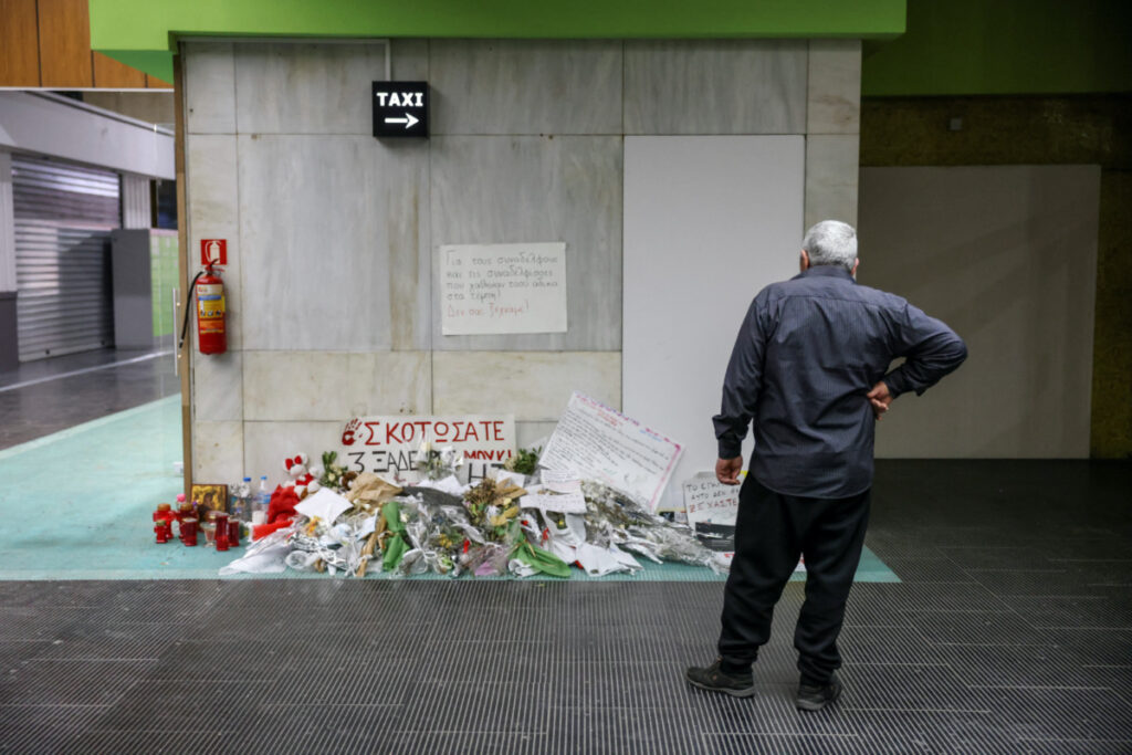 A man stands next to flowers and messages for the victims of a fatal train crash, at the closed train station of Thessaloniki, Greece, on 24th March, 2023