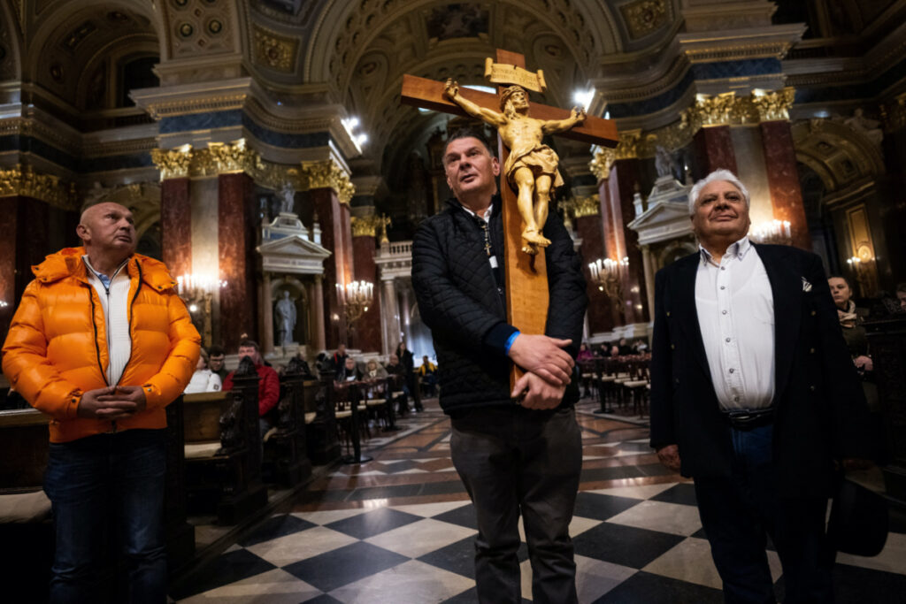 Csaba Kovesi, 50, carries a large wooden cross blessed by late Pope John Paul II and Pope Francis, alongside Vilmos Kovesi, 52, and Aladar Horvath, 71, ahead of Pope Francis' upcoming visit to Hungary, at a Basilica, in Budapest, Hungary, on 15th April, 2023.