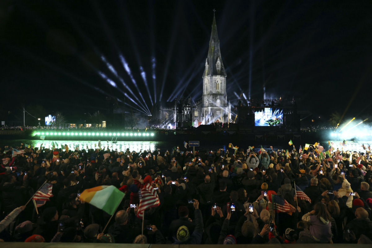 People watch a large screen showing President Joe Biden speaking outside St Muredach's Cathedral, in Ballina, Ireland, on Friday, 14th April, 2023. 
