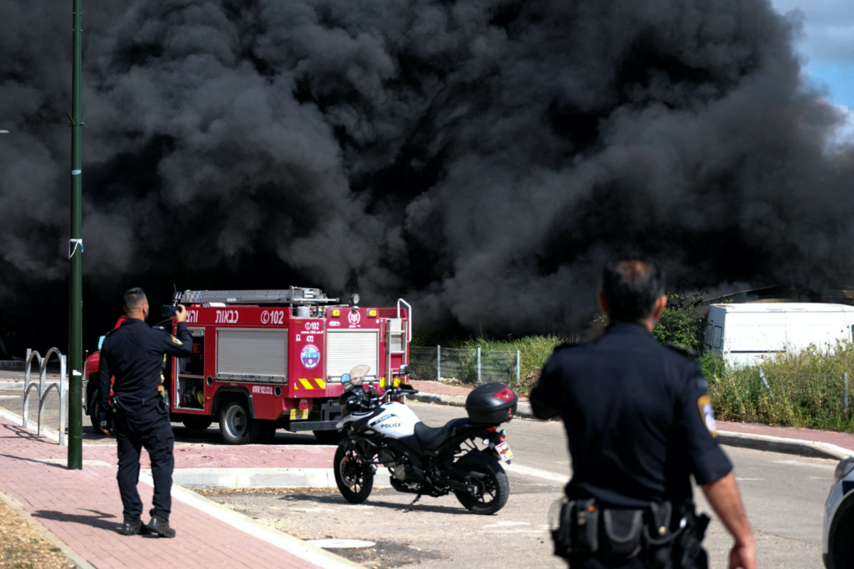 Israeli policemen stand next to smoke from a fire following incoming rockets from Lebanon to Israel in Bezet, northern Israel, on 6th April, 2023. 