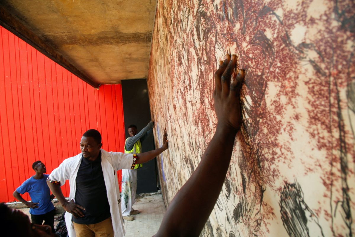 Ivorian painter Pascal Konan stands with his team while he prepares an artwork, on a facade of the 'Pyramid', the emblematic tower of the Ivorian capital built in the 1970s and has fallen into disuse for twenty years, in Abidjan, Ivory Coast, on 19th April, 2023.