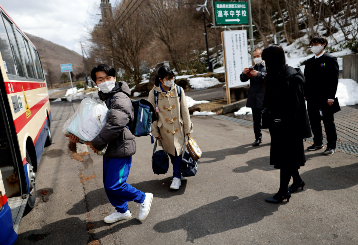 Eita Sato, 15, and Aoi Hoshi, 15, the only two students at Yumoto Junior High School, take the last school back home as their teachers see them off on the day before their graduation and the institution's closing ceremony, in Ten-ei Village, Fukushima Prefecture, Japan, on 10th March, 2023. 