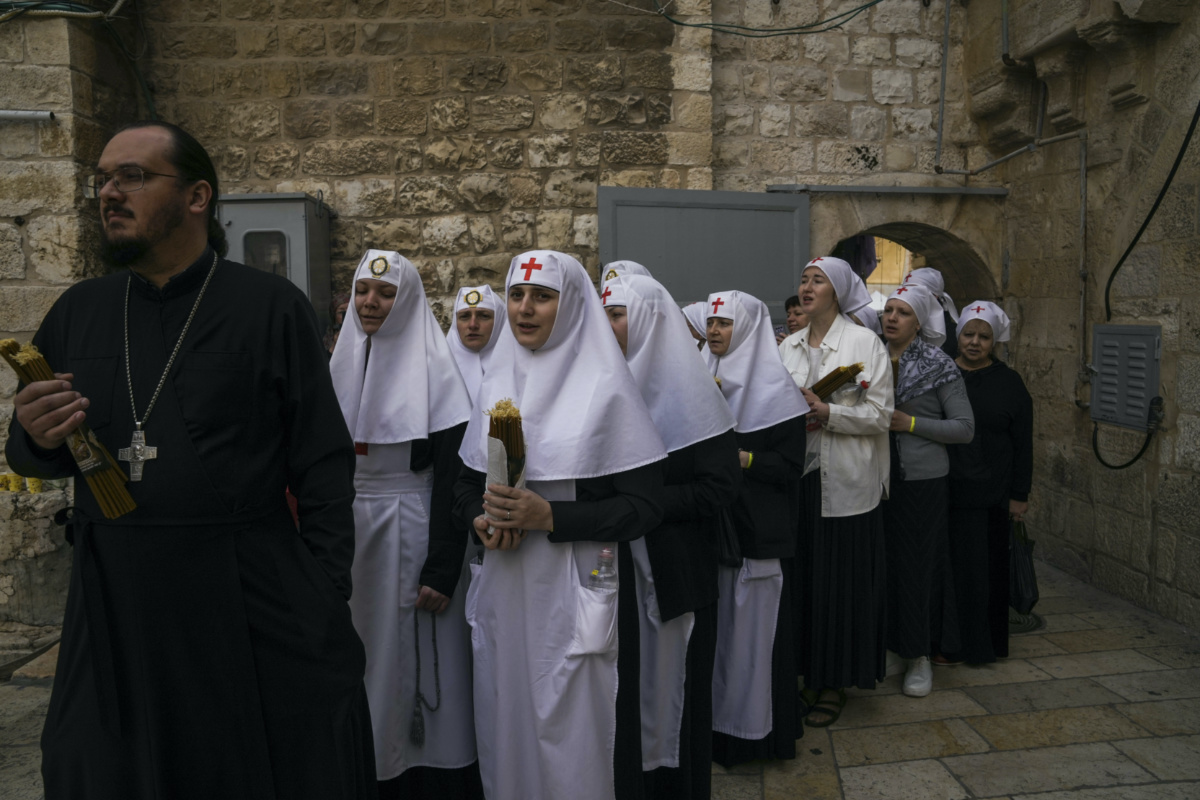 Orthodox Christians clergy and nuns hold candles as they arrive for the Holy Fire ceremony, a day before Easter, at the Church of the Holy Sepulchre, where many Christians believe Jesus was crucified, buried and resurrected, in Jerusalem's Old City, on Saturday, 15th April, 2023.