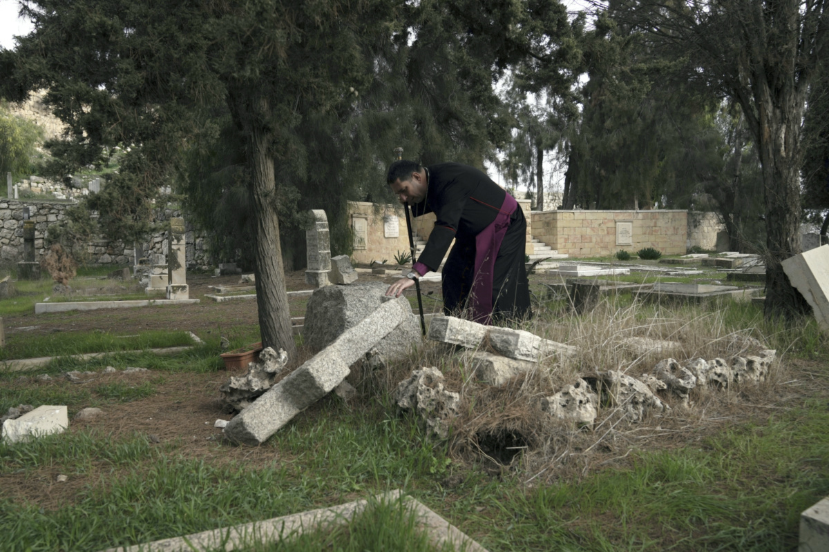 Hosam Naoum, a Palestinian Anglican bishop, touches a damaged grave where vandals desecrated more than 30 graves at a historic Protestant Cemetery on Jerusalem's Mount Zion in Jerusalem, on Wednesday, 4th January, 2023.