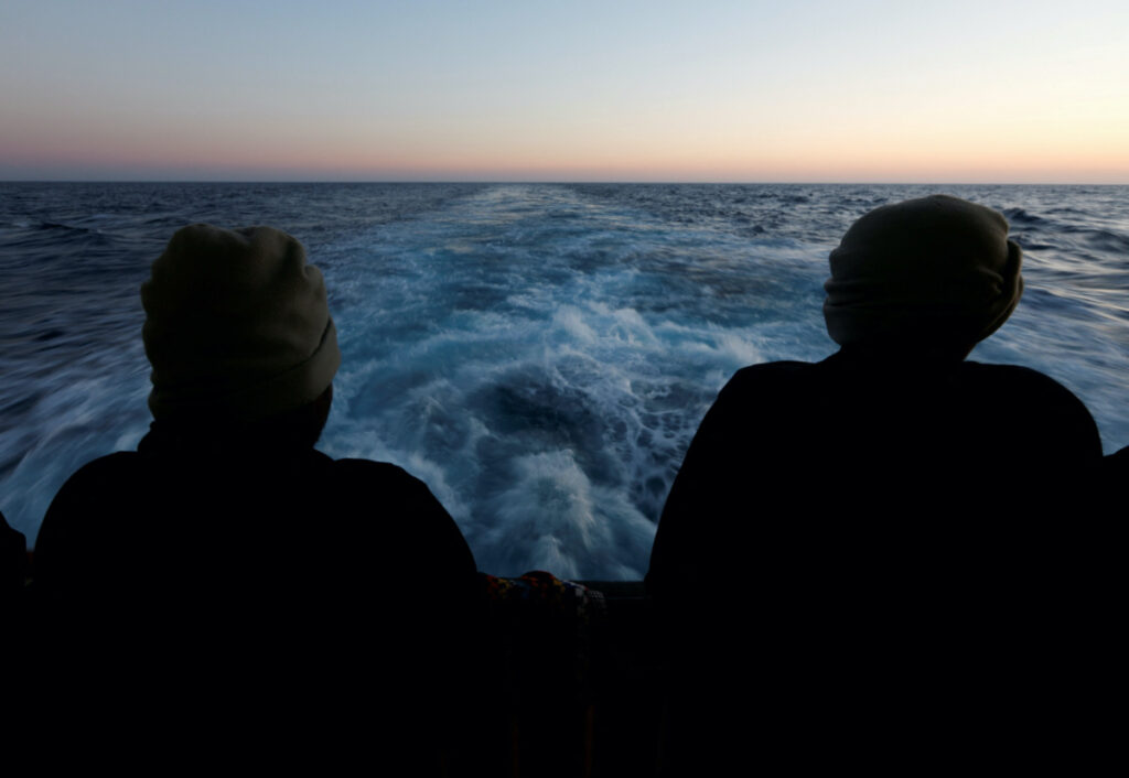 Rescued migrants look out to sea on the Geo Barents rescue ship, operated by Medecins Sans Frontieres, as the ship makes its way to the Italian port of Bari, in the central Mediterranean Sea on 25th March, 2023.