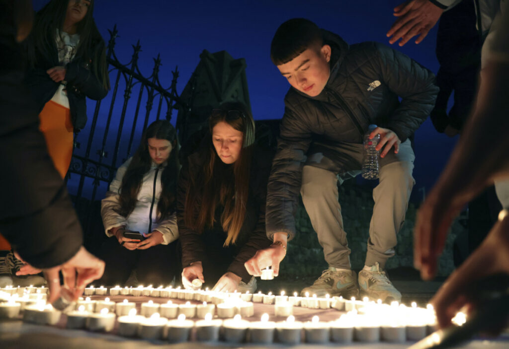 Youth from St. Peter's Immaculata Youth Centre and the Townsend Street Social Outreach Centre light candles at Belfast City cemetery for Holocaust Remembrance Day, in west Belfast, Northern Ireland, Friday, Jan. 27, 2023. Twenty-five years ago, the Good Friday Agreement halted much of the violence of Northern Ireland’s Troubles. Today, grassroots faith leaders are trying to build on that opportunity. They're working toward reconciliation in a land where religion was often part of the problem. (AP Photo/Peter Morriso