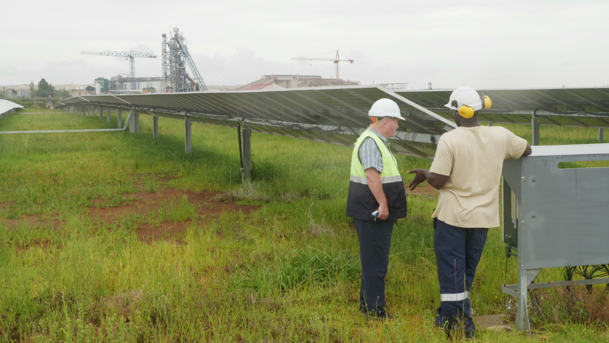 Two employees of the Pan African Resource’s gold mine talk in front of a solar farm used to power the gold mine in Mpumalanga, South Africa, on 1st February, 2023.