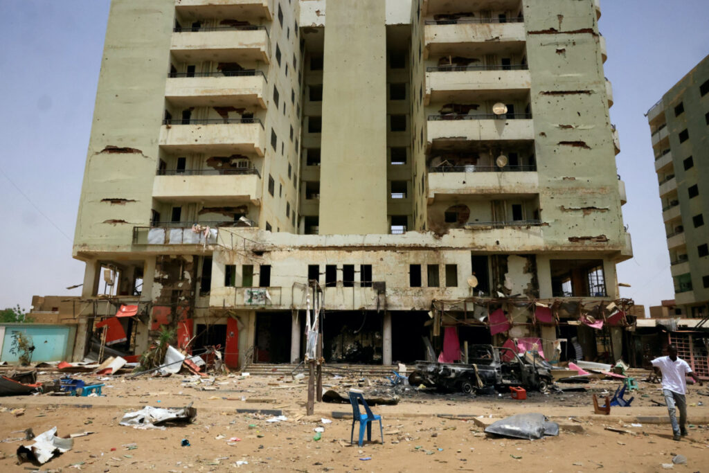A man walks past near a damaged car and buildings at the central market during clashes between the paramilitary Rapid Support Forces and the army in Khartoum North, Sudan, on 27th April, 2023.