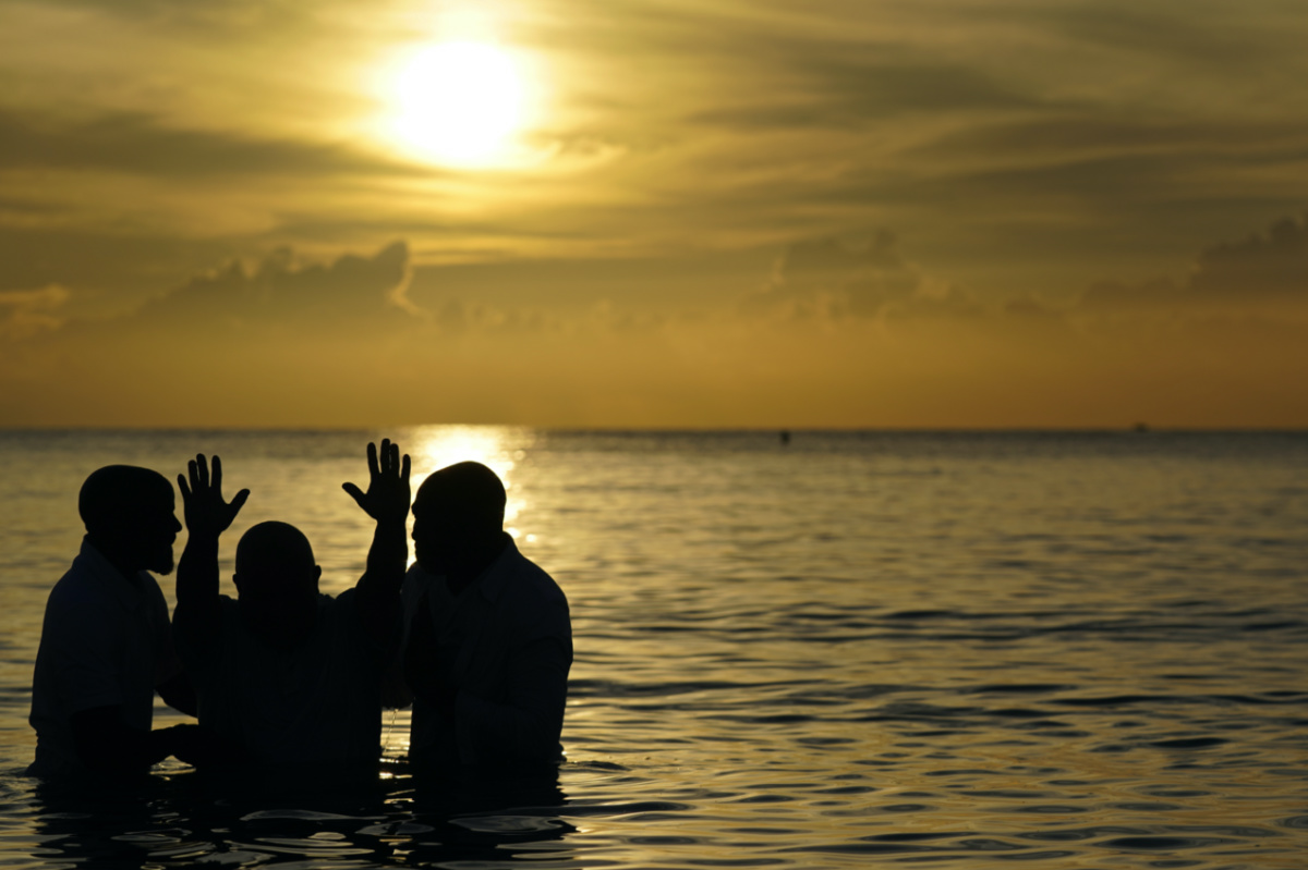 Louis "Jerry" Barrios, second from left, reacts after being baptised by co-pastors Rev Brian Glasford, right, and his brother Rev Jason Glasford, left, in the Atlantic Ocean during an Easter sunrise service with the New Life Missionary Baptist Church, on Sunday, 9th April, 2023, in Miami Beach, Florida.