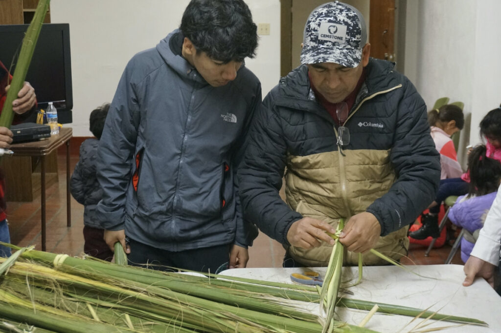 Reynaldo Hidalgo, right, teaches a volunteer how to weave palm fronds at the Church of the Incarnation in Minneapolis on Wednesday, on 29th March, 2023.