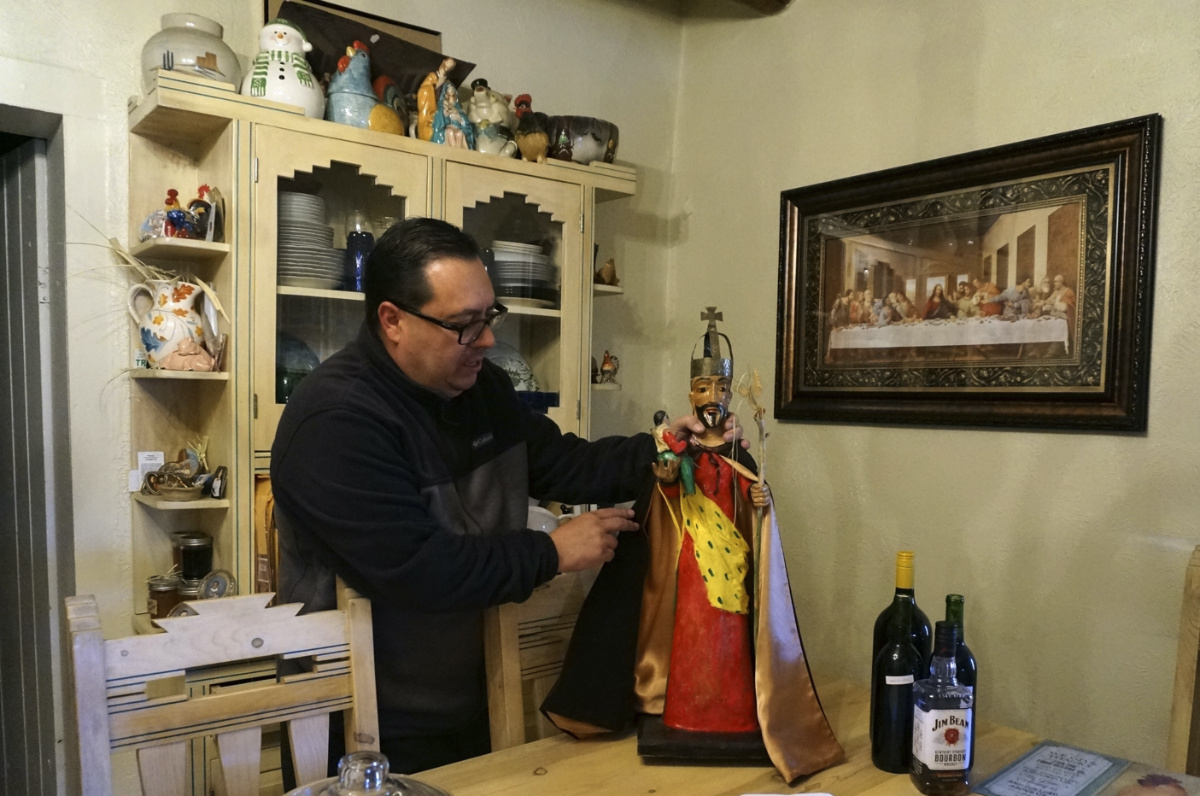 Mayordomo Fidel Trujillo adjusts the cape on his bulto, or wooden sculpture of St Joseph, that's kept for safekeeping at his aunt's home in Ledoux, New Mexico, on Saturday, 15th April, 2023. 
