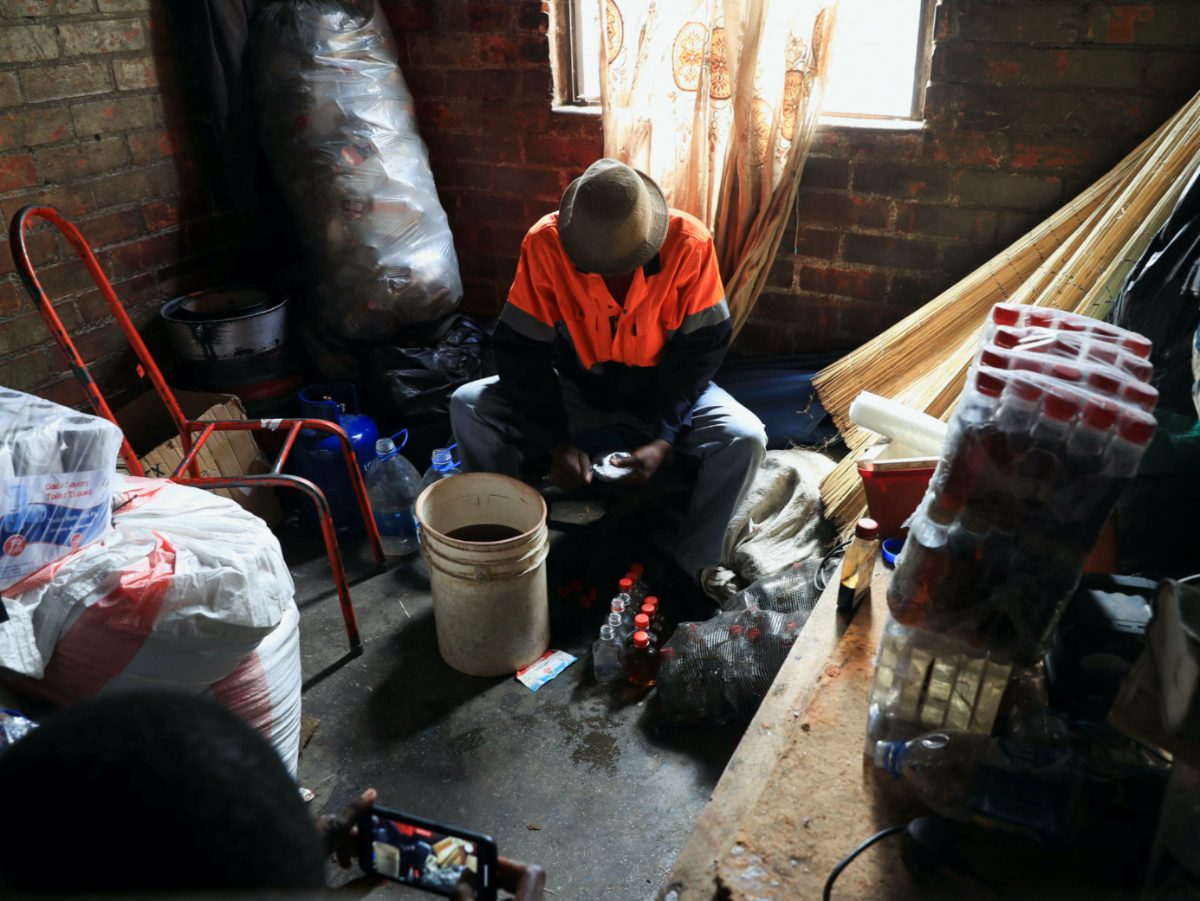 A man sits in an informal brewing facility that makes fake whisky, brandy, vodka and other spirits, in Harare, Zimbabwe, on 23rd March, 2023
