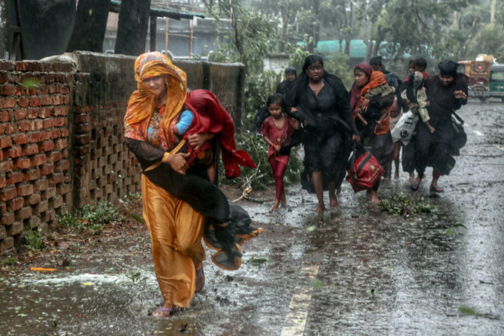People move from their homes to take shelter in the nearest cyclone shelter at Shah Porir Dwip during the landfall of cyclone Mocha in Teknaf, Bangladesh, on 14th May, 2023.