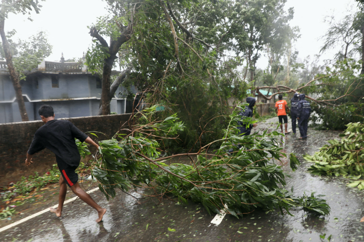 People move fallen trees from a road at Shah Porir Dwip after the landfall of cyclone Mocha in Teknaf, Bangladesh, on 14th May, 2023.