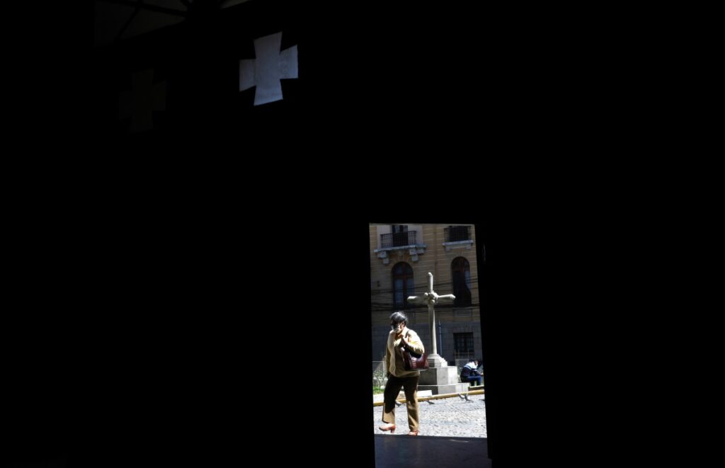 A woman, framed by a doorway of the Merced Catholic Church, walks past in La Paz, Bolivia, on Tuesday, 2nd May, 2023.