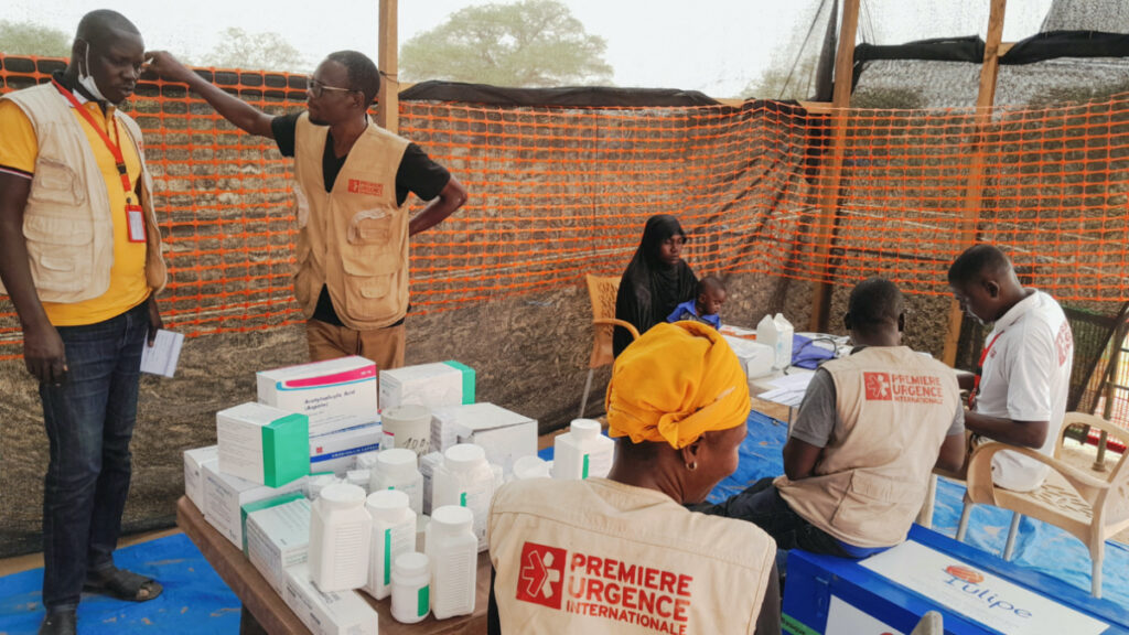 Members of the NGO Premiere Urgence Internationale receive a Sudanese refugee who fled the violence in her country as she gathers with other refugees near the border between Sudan and Chad, in Koufroun, Chad, on 29th April, 2023.
