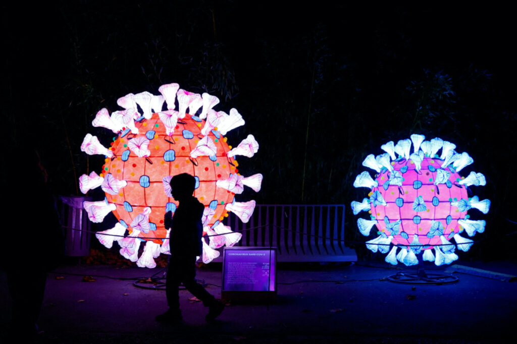 A visitor walks past an illuminated coronavirus model as he visit the "Mini-Worlds on the Way of Illumination" exhibition during the Light Festival preview at the Jardin des Plantes (Botanical garden) in Paris, France, on 12th November, 2022