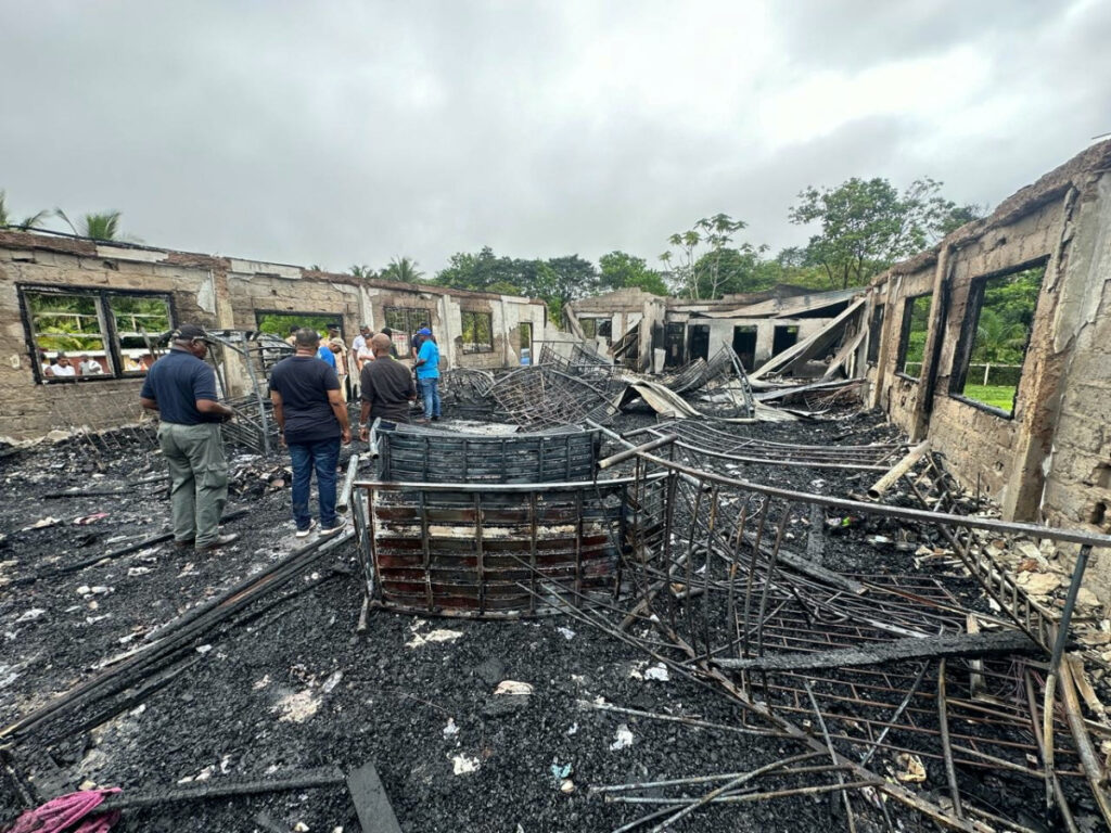 People stand inside the remains of a burnt secondary school dormitory after several children, most of them from indigenous communities, died after a fire gutted the building overnight, in Mahdia, Guyana in this handout image obtained by Reuters on 22nd May, 2023