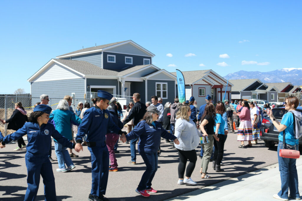 Attendings participate in a traditional round dance showcasing friendship, led by the Native American Women's Association, during the dedication of a Pikes Peak Habitat for Humanity Interfaith Build for Unity home, shown in rear, on 29th April, 2023, in Colorado Springs, Colorado.
