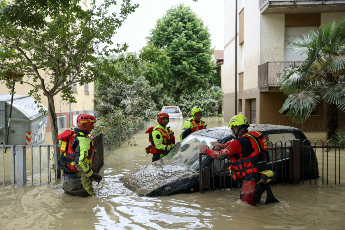 Firefighters work next to a flooded car, after heavy rains hit Italy's Emilia Romagna region, in Faenza, Italy, on 18th May, 2023.