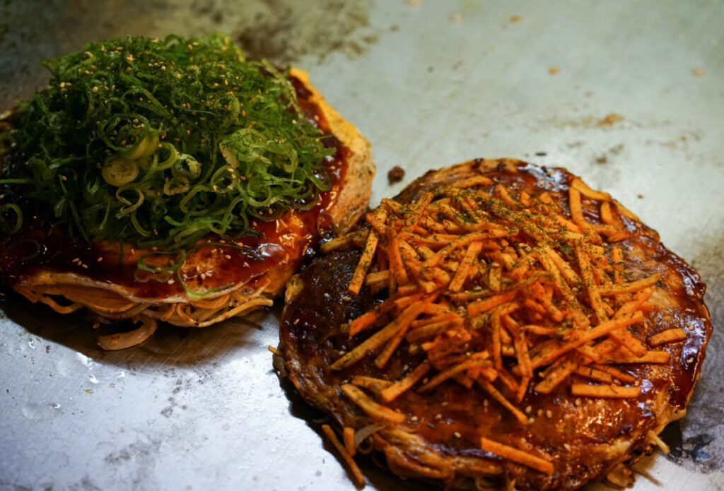 Okonomiyaki, a pancake-shaped mix of noodles, cabbage, egg, meat and seafood, topped with a distinctive sweet and sour sauce and fried on a hot metal plate, are seen at a okonomiyaki specialty chain Chinchikurin restaurant in Hiroshima, western Japan, on 8th May, 2023