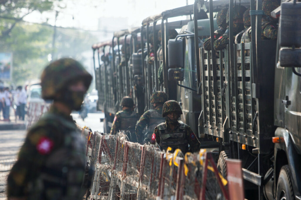 Soldiers stand next to military vehicles as people gather to protest against the military coup, in Yangon, Myanmar, on 15th February, 2021.