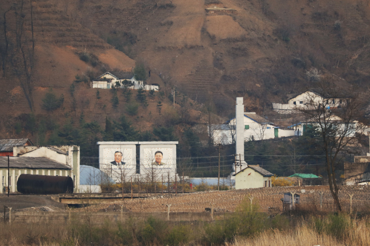 Buildings in North Korea's Sinuiju with giant portraits of late North Korean leaders Kim Il Sung and Kim Jong Il are seen from China's Dandong, Liaoning province, China, on 20th April, 2021. 