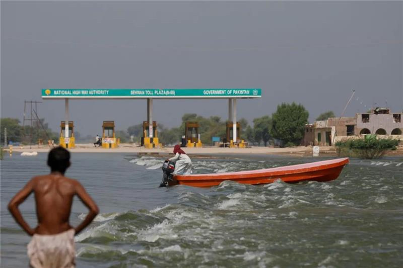 A man rides a boat past toll plaza amid flood water on main Indus highway, following rains and floods during the monsoon season in Sehwan, Pakistan, on 15th September, 2022