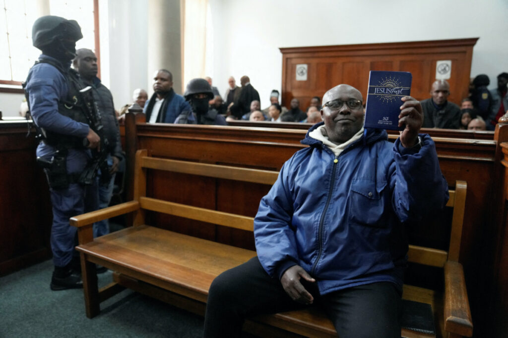 Rwandan genocide suspect Fulgence Kayishema holds up a Christian book, as he appears in the Cape Town Magistrates Court, in Cape Town, South Africa, on 26th May, 2023.