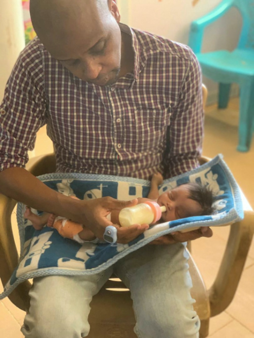 Dr Abdallah Kenany feeds a newborn baby, who died a few days later, in Khartoum, Sudan, in this handout image released in April 2023. 