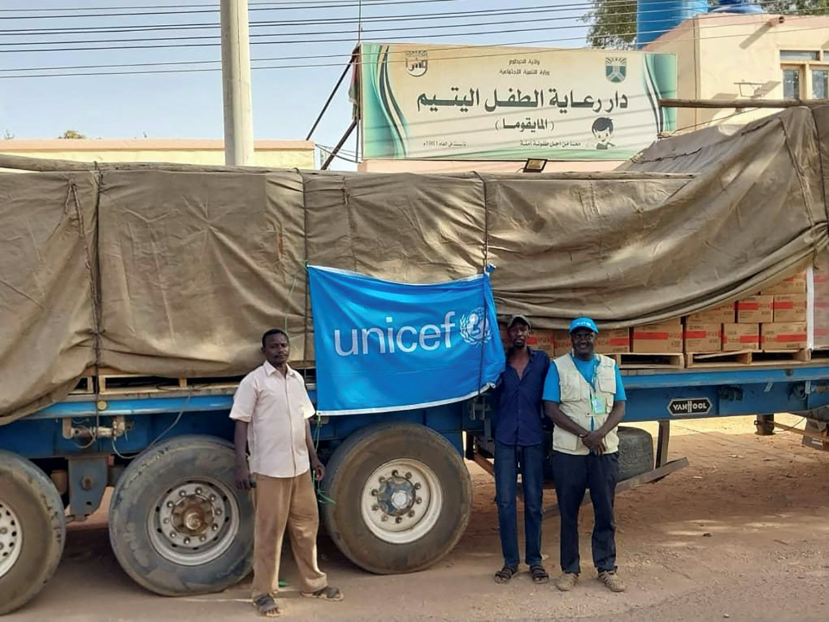 People stand next to a UNICEF flag attached to a truck, in Khartoum, Sudan, in this handout image released on 18th May, 2023. 