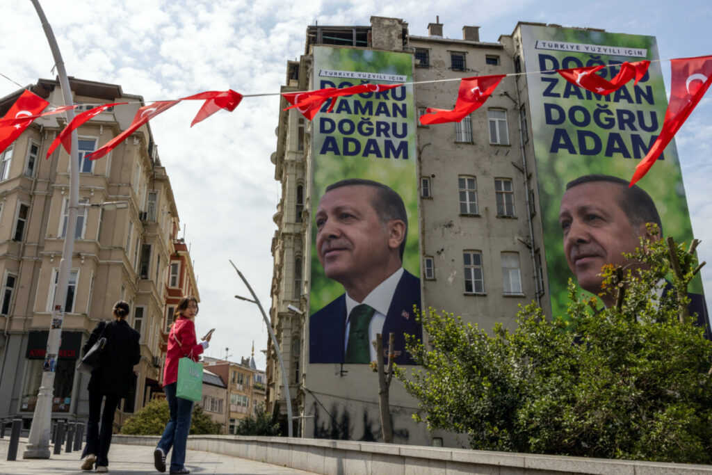 People walk next to posters of Turkish President Tayyip Erdogan, ahead of the 28th May presidential runoff vote, in Istanbul, Turkey, on 25th May, 2023.