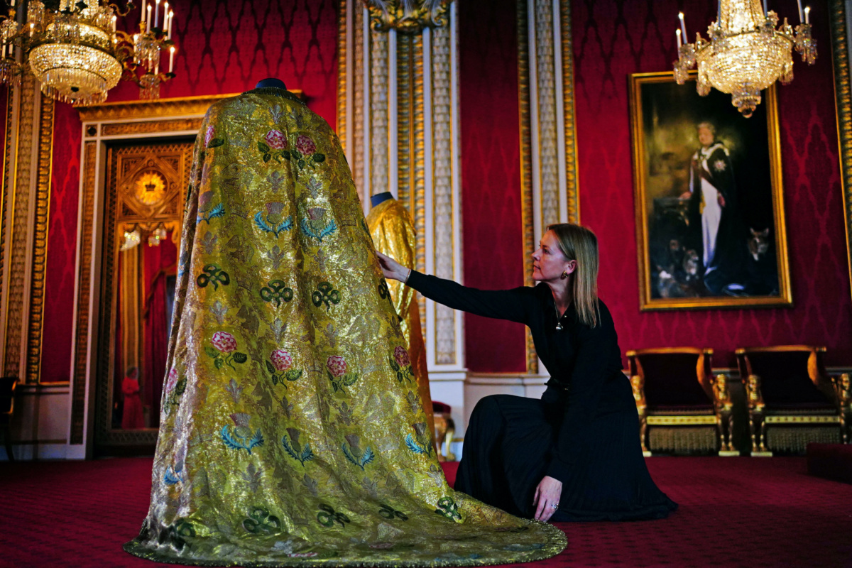 Caroline de Guitaut, deputy surveyor of the King's Works of Art for the Royal Collection Trust, adjusts the Imperial Mantle, which forms part of the Coronation Vestments and will be worn by Britain's King Charles during his coronation at Westminster Abbey, in the Throne Room at Buckingham Palace, London, Britain, on 26th April, 2023