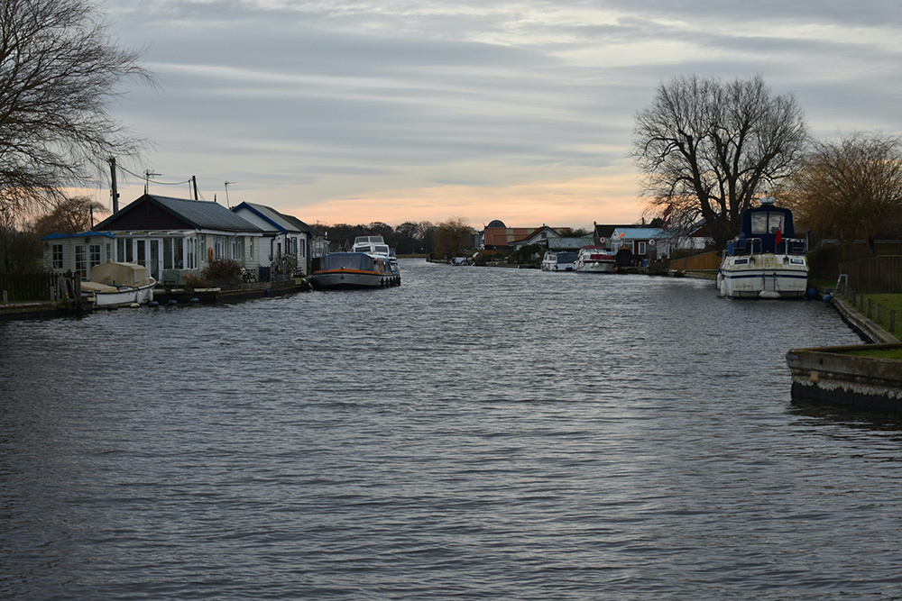 Homes and boats on the River Thurne in the village of Potter Heigham in the Broads, east England, on 10th February, 2023