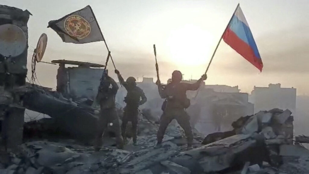 Wagner mercenary group fighters wave flags of Russia and Wagner group on top of a building in an unidentified location, in the course of the Russia-Ukraine conflict, in this still image obtained from a video released on 20th May, 2023