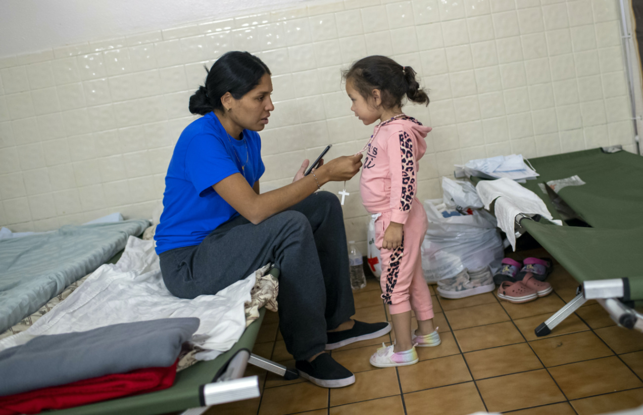 Venezuelan migrant Juaniela Castillo adjust a rosary necklace on her daughter Victoria, three, inside a shelter at St Francis Xavier Church in El Paso, Texas, on Thursday, 11th May, 2023. 